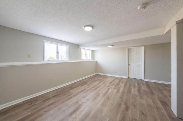 below grade area featuring baseboards, a textured ceiling, and wood finished floors