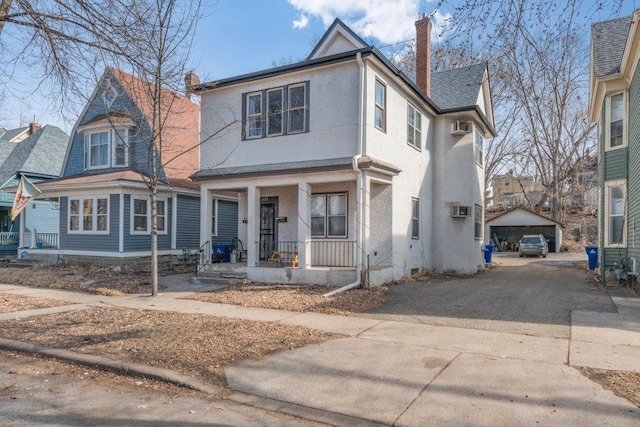 view of front of home featuring stucco siding, a porch, a chimney, and driveway