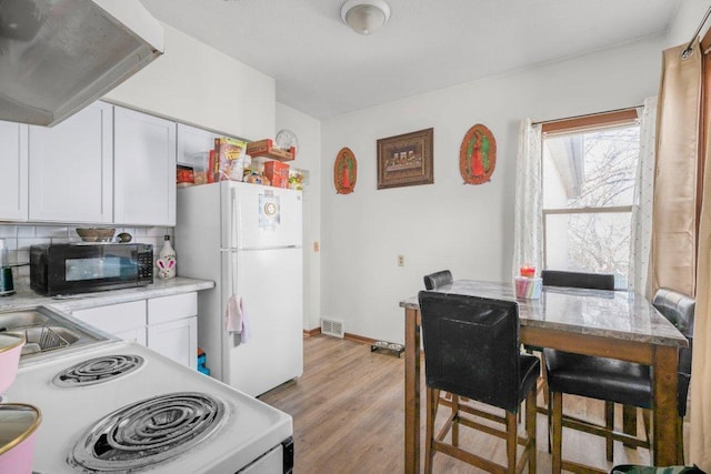 kitchen featuring white appliances, visible vents, light wood-type flooring, white cabinetry, and tasteful backsplash