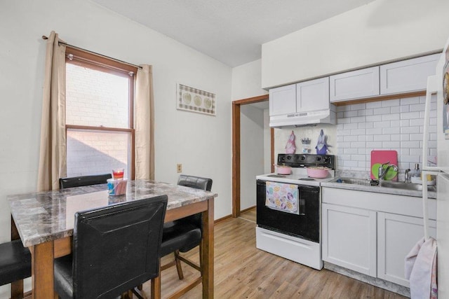 kitchen featuring range with electric cooktop, under cabinet range hood, a sink, light wood-style floors, and decorative backsplash