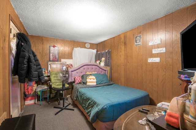 carpeted bedroom featuring wood walls and a textured ceiling