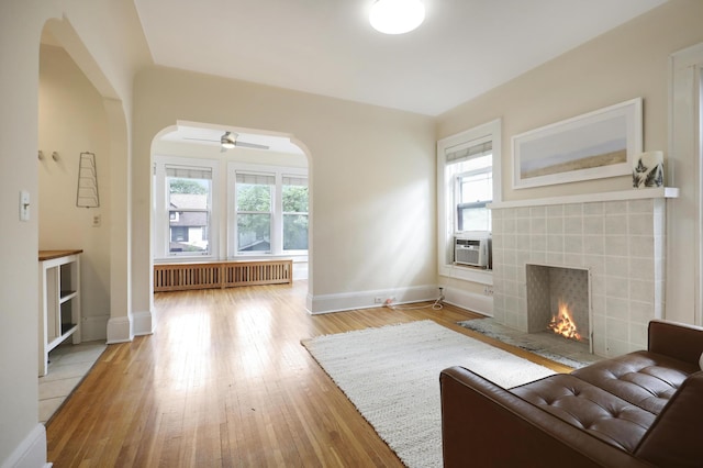 2606 Humboldt Ave S Unit 6, Minneapolis, MN 55408 - living room featuring arched walkways, radiator, a tiled fireplace, and baseboards