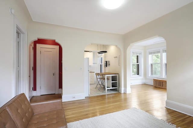 2606 Humboldt Ave S Unit 6, Minneapolis, MN 55408 - unfurnished living room with radiator heating unit, arched walkways, light wood-style flooring, and baseboards