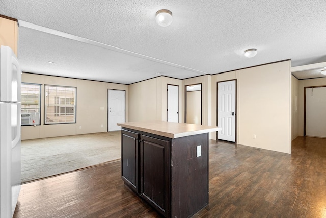 kitchen featuring dark wood-style floors, dark brown cabinets, light countertops, and freestanding refrigerator