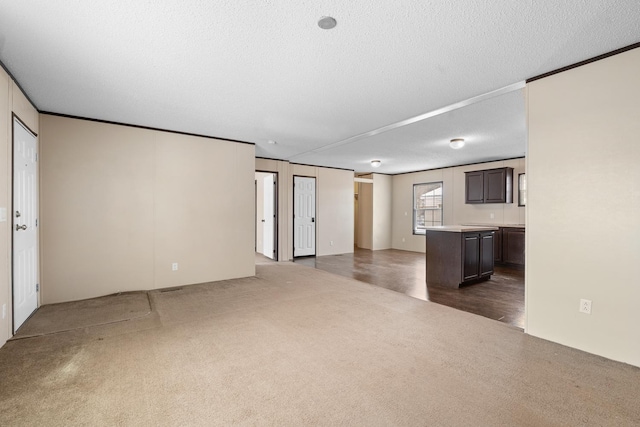 unfurnished living room with dark carpet, a textured ceiling, and crown molding