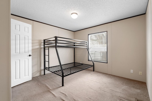 unfurnished bedroom with crown molding, carpet flooring, and a textured ceiling