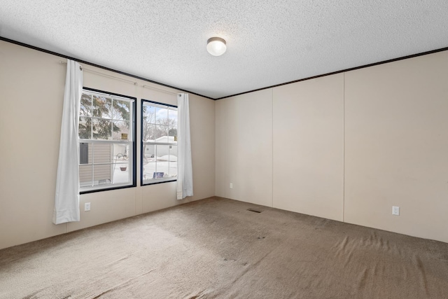 carpeted empty room with visible vents, a textured ceiling, and crown molding