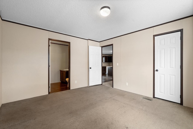 unfurnished bedroom featuring ornamental molding, a textured ceiling, and carpet floors