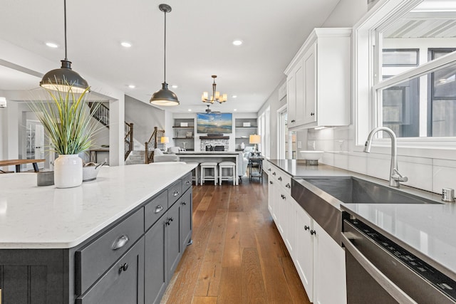 kitchen with white cabinetry, stainless steel dishwasher, a sink, dark wood-style flooring, and recessed lighting