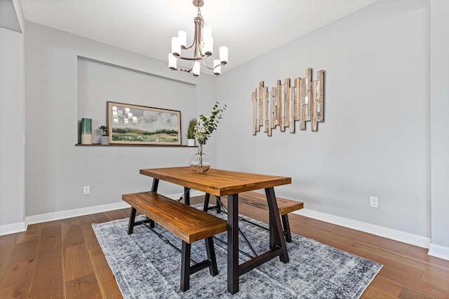 dining space featuring a chandelier, hardwood / wood-style floors, and baseboards