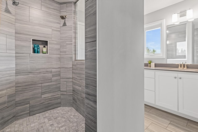 bathroom featuring tiled shower and vanity