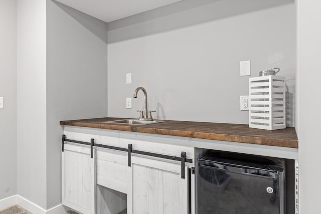 interior space featuring wooden counters, a sink, dishwashing machine, and baseboards