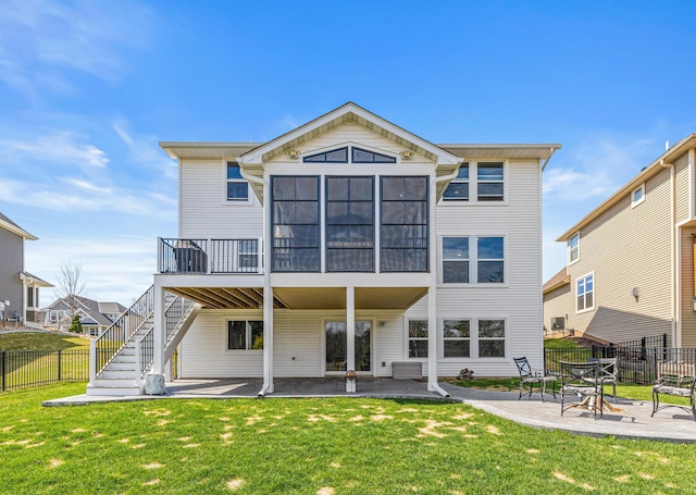 back of house featuring a sunroom, stairway, a patio area, a lawn, and fence