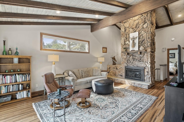 living area with wood finished floors, baseboards, vaulted ceiling with beams, a stone fireplace, and wooden ceiling