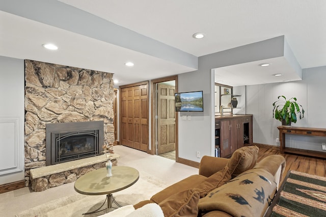 living room with a stone fireplace, recessed lighting, light wood-style flooring, and baseboards