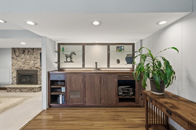 bar featuring recessed lighting, a stone fireplace, and light wood finished floors