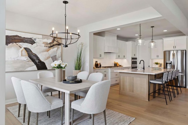 dining room featuring recessed lighting, light wood-style floors, and an inviting chandelier