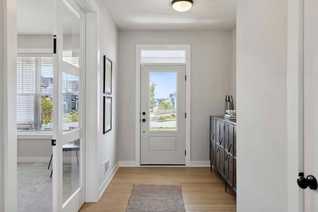 doorway featuring visible vents, light wood-type flooring, and baseboards