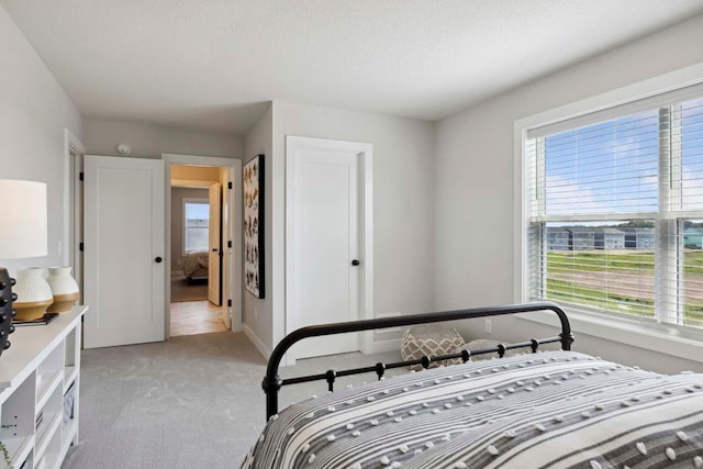 bedroom with light carpet, a textured ceiling, and baseboards