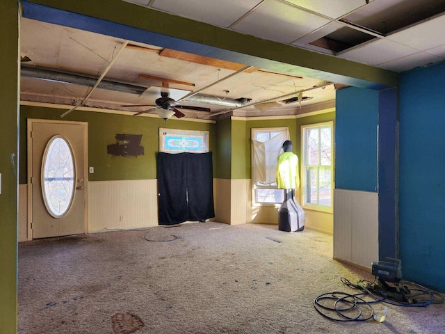 carpeted empty room with a ceiling fan and wainscoting