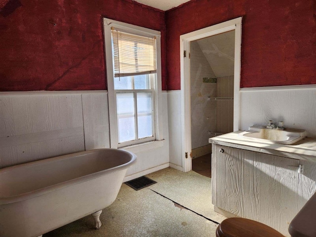 bathroom with visible vents, vanity, a freestanding bath, and wainscoting