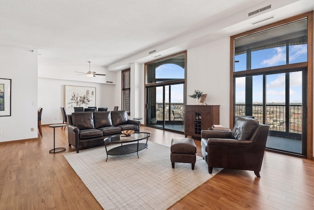 living area featuring plenty of natural light, wood finished floors, visible vents, and baseboards