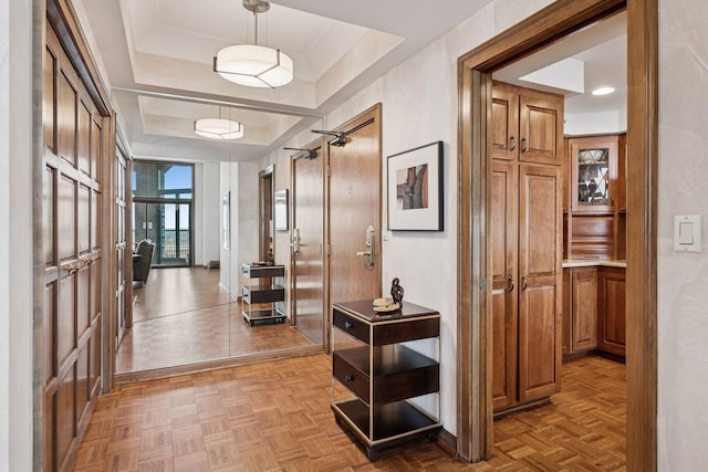 hallway with baseboards and a tray ceiling