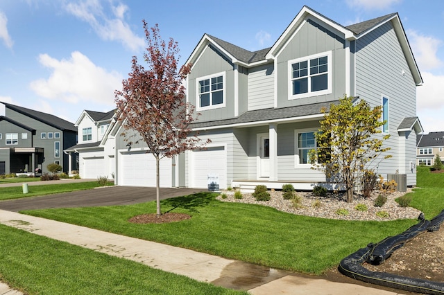 view of front of home with a front lawn, roof with shingles, board and batten siding, and driveway