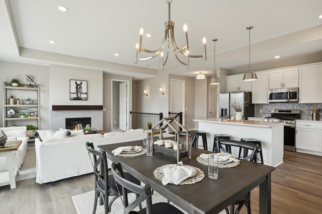 dining area featuring dark wood finished floors, recessed lighting, and a lit fireplace