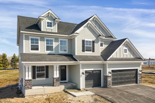 craftsman house with stone siding, a porch, driveway, and a shingled roof