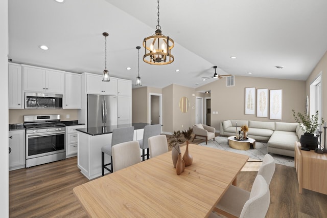 dining area with recessed lighting, ceiling fan with notable chandelier, dark wood-type flooring, and vaulted ceiling