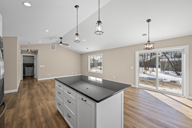 kitchen featuring lofted ceiling, dark countertops, a healthy amount of sunlight, and white cabinetry