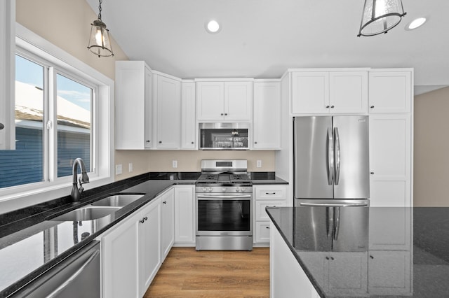 kitchen featuring a sink, appliances with stainless steel finishes, light wood-style flooring, and white cabinets