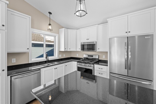 kitchen featuring pendant lighting, a sink, appliances with stainless steel finishes, white cabinets, and lofted ceiling