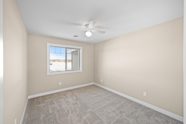 carpeted empty room with baseboards and a ceiling fan