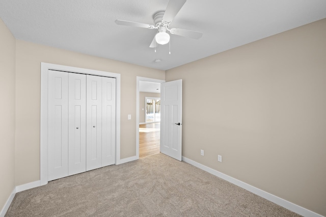 unfurnished bedroom featuring a closet, baseboards, a ceiling fan, and carpet flooring