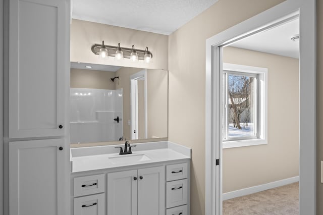 bathroom with baseboards, a textured ceiling, walk in shower, and vanity