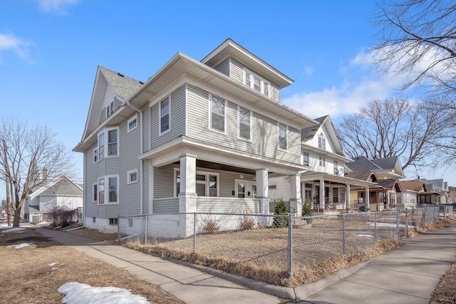 american foursquare style home featuring covered porch and a fenced front yard