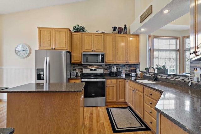 kitchen featuring tasteful backsplash, a center island, light wood-style flooring, appliances with stainless steel finishes, and a sink