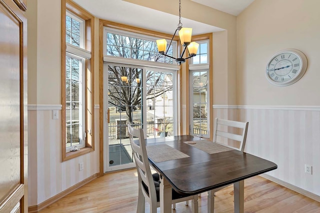 dining space with wallpapered walls, baseboards, light wood-type flooring, and a chandelier