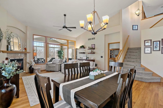 dining area featuring light wood-type flooring, visible vents, stairs, and ceiling fan with notable chandelier