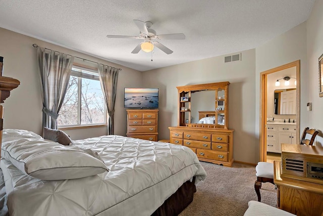 bedroom with visible vents, light colored carpet, connected bathroom, and a textured ceiling