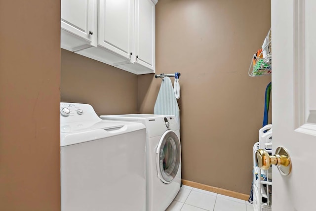 laundry room featuring washer and dryer, baseboards, cabinet space, and light tile patterned flooring