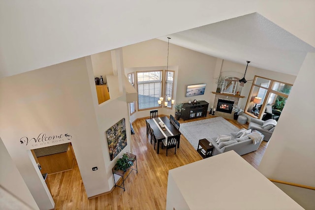 living room with plenty of natural light, a fireplace, light wood finished floors, and high vaulted ceiling