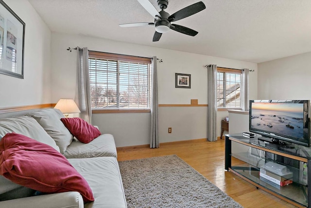 living area with a ceiling fan, wood finished floors, and a textured ceiling