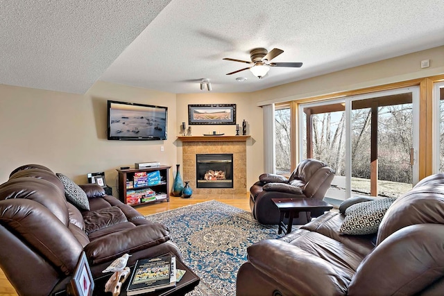 living room with a fireplace, wood finished floors, a ceiling fan, and a textured ceiling