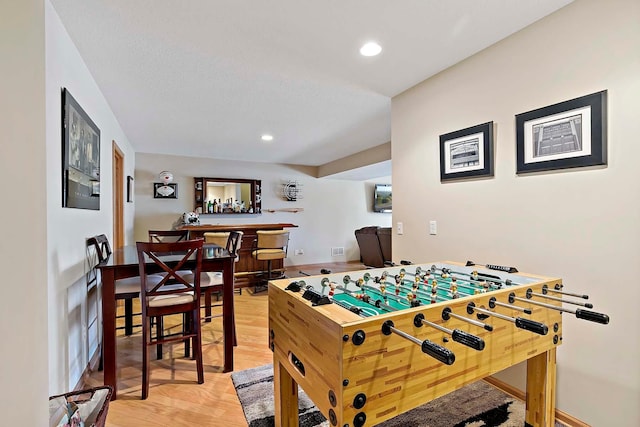 recreation room with a bar, recessed lighting, light wood-type flooring, and baseboards