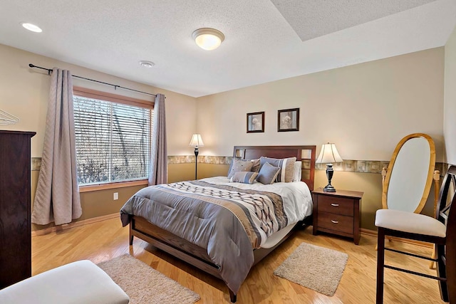 bedroom with wood finished floors, baseboards, and a textured ceiling