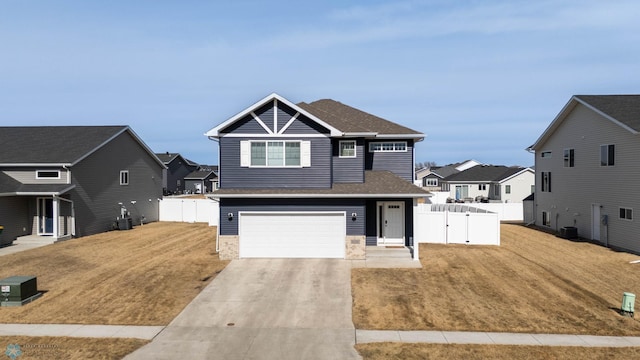 view of front of house featuring a garage, concrete driveway, a front yard, and fence