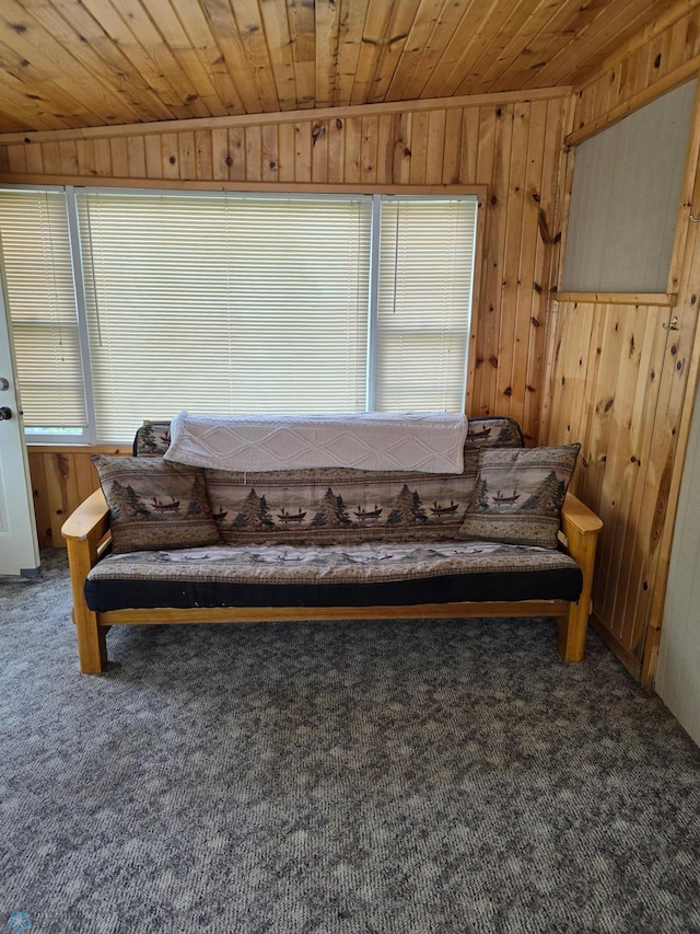 carpeted living area with wood ceiling and wood walls